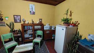 a kitchen with a refrigerator and two chairs and a book shelf at Habitación estilo vintage cerca de La Merced in Antigua Guatemala