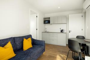 a living room with a blue couch and yellow pillows at Sunset Views Matarangi in Matarangi