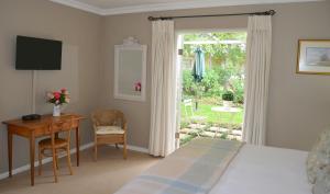 a bedroom with a bed and a desk and a window at Millpond House in Clarens