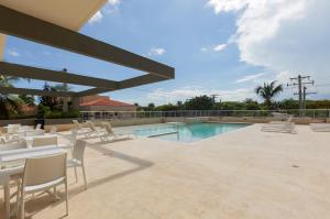 a patio with white chairs and a swimming pool at Juan Dolio RD Beach Retreat in Juan Dolio