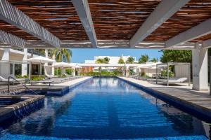 an infinity pool with chairs and umbrellas at a resort at 3BR Beachfront Luxury Condo w/ Great Features in Cancún +63 photos