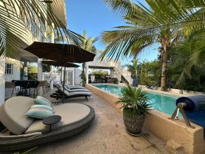 a resort with a pool with chairs and an umbrella at Casa Arena in Lo de Marcos