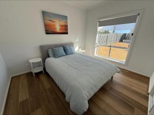 a bedroom with a bed and a window with a beach at Sea Escape in Point Turton