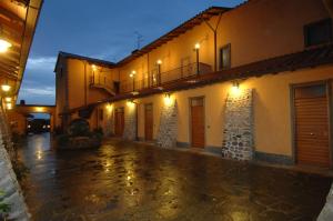 una calle vacía por la noche con edificios iluminados en Casale Certosa en Pavona