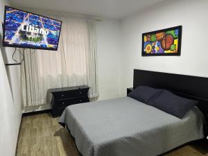 a bedroom with a bed and a flat screen tv at Apartamentos FM 202 in Líbano