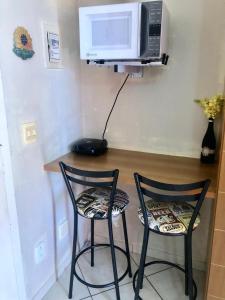 two chairs sitting next to a table with a microwave at Thermas Place Flat in Caldas Novas