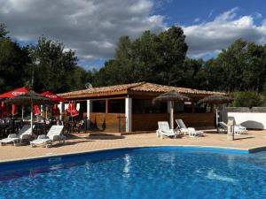 a swimming pool with chairs and umbrellas next to at Mobil-home confortable avec terrasse pour 4 personnes - API-1-52-413 in Massillargues-Attuech