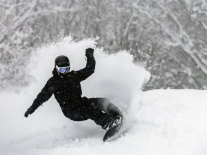 a man riding a snowboard down a snow covered slope at Hotel Alpen Blick in Myoko