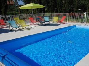 un gruppo di sedie e un ombrellone accanto a una piscina di Mobil-home 4 pers avec terrasse au camping Les Tournesols - API-1-52-489 a Crissé