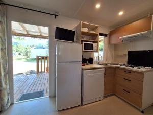 a kitchen with a white refrigerator and a balcony at Mobil-home 3 chambres avec terrasse à Valbonnais - API-1-52-473 in Valbonnais