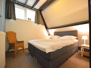 a bedroom with a bed and a chair and a window at Holiday Home in Stramproy near Nature in Stramproy