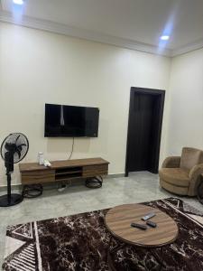 アブジャにあるIlham Suitesのテレビ、ソファ、テーブルのあるリビングルーム