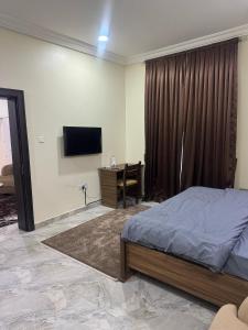 アブジャにあるIlham Suitesのベッドと机とテレビのある寝室