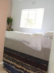 a bedroom with a bed with white sheets and a window at KAREN 2Bdrm NEAR NATIONAL PARK in Nairobi