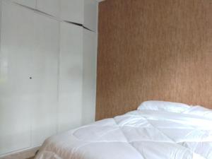 a bedroom with a white bed and a wall at KAREN 2Bdrm NEAR NATIONAL PARK in Nairobi