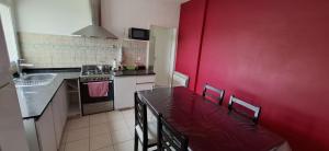 a kitchen with a red wall and a table and chairs at Como en casa CRD 2 in Comodoro Rivadavia