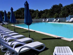 a row of chairs and umbrellas next to a swimming pool at Chalet 3 chambres avec terrasse pour 5 personnes - API-1-52-617 in Rives