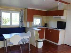 a small kitchen with a table and chairs in it at Mobil home avec terrasse pour 4 personnes - API-1-52-649 in La Mothe-Achard +13 photos