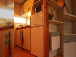 Elle comprend une petite cuisine avec un réfrigérateur et quelques étagères. dans l'établissement Mobil-home 7 pers avec terrasse - API-1-52-737, à Esparron-de-Verdon