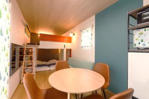 a room with a table and chairs and a bunk bed at ホテルトレーラーシップガーデン阿蘇 in Aso