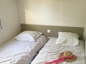 a bed with a hat on it with two pillows at Mobil-home pour 6 avec terrasse à Avrillé - API-1-52-728 in Avrillé