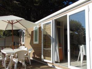 a house with a table and chairs and an umbrella at Mobil-home pour 6 avec terrasse à Avrillé - API-1-52-728 in Avrillé