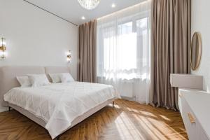 a white bedroom with a bed and a large window at GreenLine Atmosfera luxe 2 bedroom apartment in Zhezdi