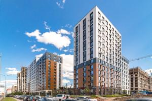 a tall building with cars parked in a parking lot at GreenLine Atmosfera luxe 2 bedroom apartment in Zhezdi