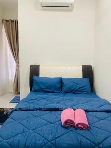a blue bed with two pink slippers on it at ZuLee Homestay in Lunas