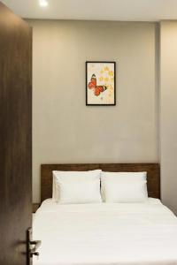 a bed with white sheets and a picture on the wall at Hoàng Anh Apartment in Da Nang
