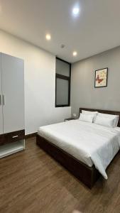 a bedroom with a large white bed and a tv at Hoàng Anh Apartment in Da Nang