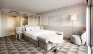 Un dormitorio con una gran cama blanca y una silla. en InterContinental Sydney Coogee Beach by IHG, en Sídney 12 fotos más