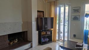 ein Wohnzimmer mit Kamin und Flachbildfernseher in der Unterkunft Almiva in Panagioúda
