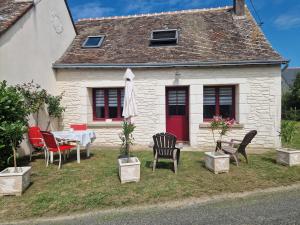 una casa con mesa, sillas y sombrilla en MAISON à la CAMPAGNE, en Hommes