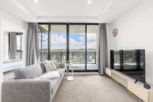 ein Wohnzimmer mit Couch und Flachbildfernseher in der Unterkunft Cozy Lyneham Retreat, Views, Gym n Free Parking in Downer