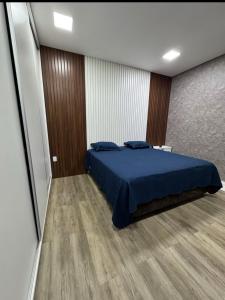a bedroom with a blue bed and a wooden wall at Aconchego in Cáceres