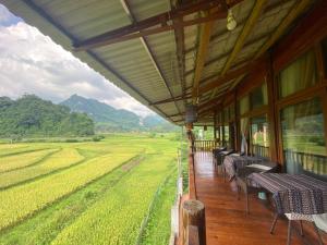 a porch of a house with tables and chairs and a field at Ecolodge Đồng Lâm Homestay in Hữu Lũng