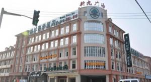 a large building with a clock on the top of it at GreenTree Inn Shanghai Songjiang Xinqiao Jiuxin Road Express Hotel in Chunshen
