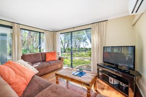 Una sala de estar con un sofá y un televisor de pantalla plana. en 98 Steps to the Beach 2BR Coastal Getaway, en Broadwater