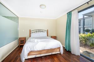 Un dormitorio con una cama y una ventana grande. en 98 Steps to the Beach 2BR Coastal Getaway, en Broadwater 10 fotos más