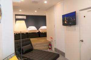 Cette chambre comprend un lit, un canapé et une télévision. dans l'établissement YadoyaTamachi 101, à Tokyo