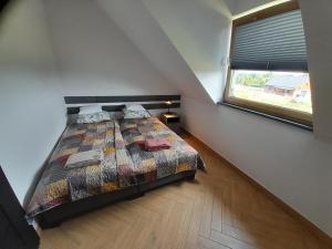 a bedroom with a bed with a comforter and a window at Apartamenty Babie Lato in Białogóra