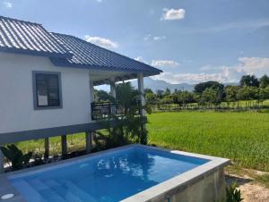 贡布Baksaei Retreat Ricefield Villas的一座带田野的房屋前的游泳池