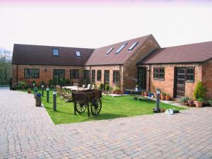 a brick building with a horse drawn carriage in front of it at Church Farm Barns in Stratford-upon-Avon