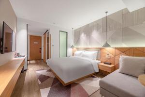 a bedroom with a large white bed and a couch at Borrman Hotel Jining Rencheng District Government Zhongde Plaza in Jining