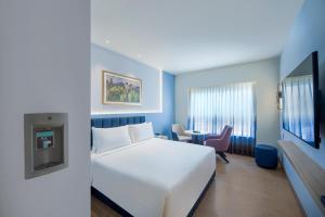 a hotel room with a white bed and a desk at Sarovar Portico Sriperumbudur in Sriperumbudur