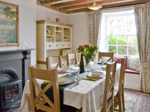 a dining room with a table and chairs and a fireplace at Cherry Tree Cottage in Bellerby