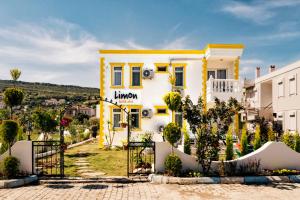 una casa amarilla y blanca con una puerta delante en Limon Pansiyon en Foca