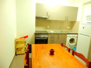 una cucina con tavolo in legno e una cucina con lavandino di Squash Club Apartamentos a Portimão