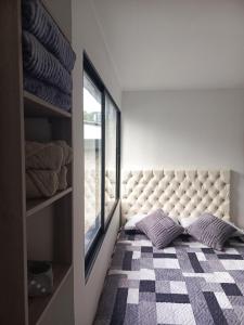 a bedroom with a tufted bed with a window at Casa Manila Medellin in Medellín